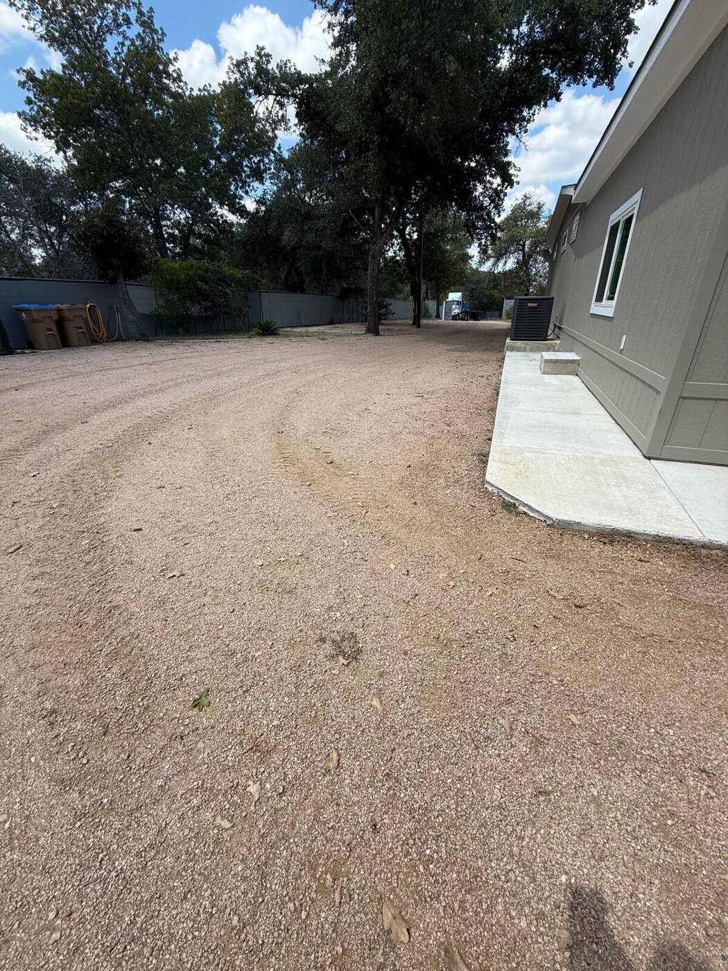 Freshly graded gravel driveway alongside a new home