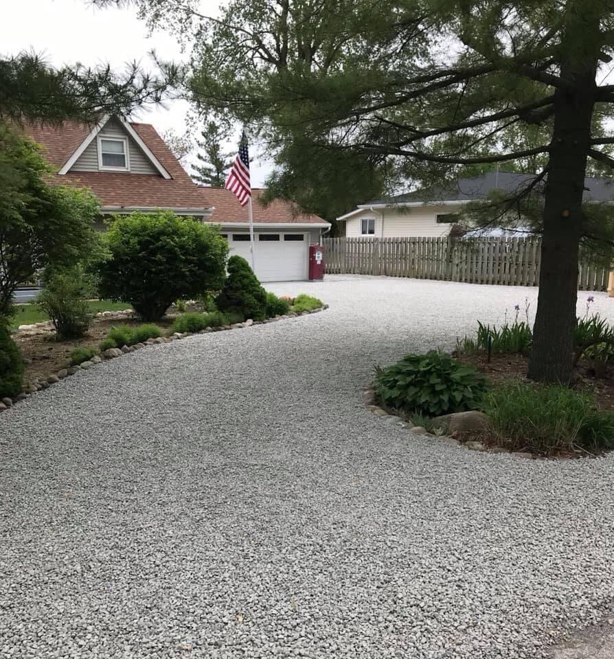 Curved gravel driveway with stone borders and landscaping