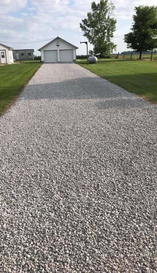 Long crushed stone driveway leading to a detached garage