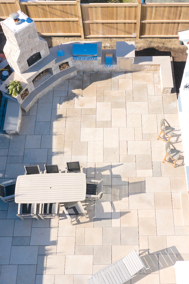 Aerial view of a paver brick patio with fireplace and dining area