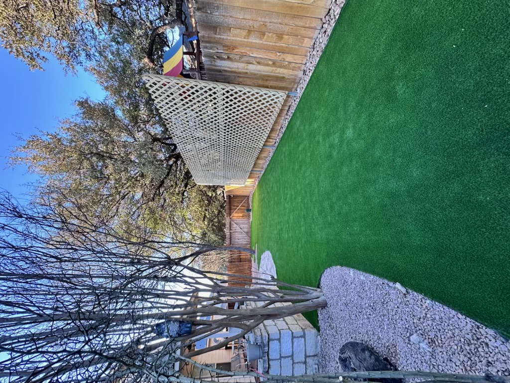 Pet-friendly artificial turf side yard with stone border and lattice privacy screen