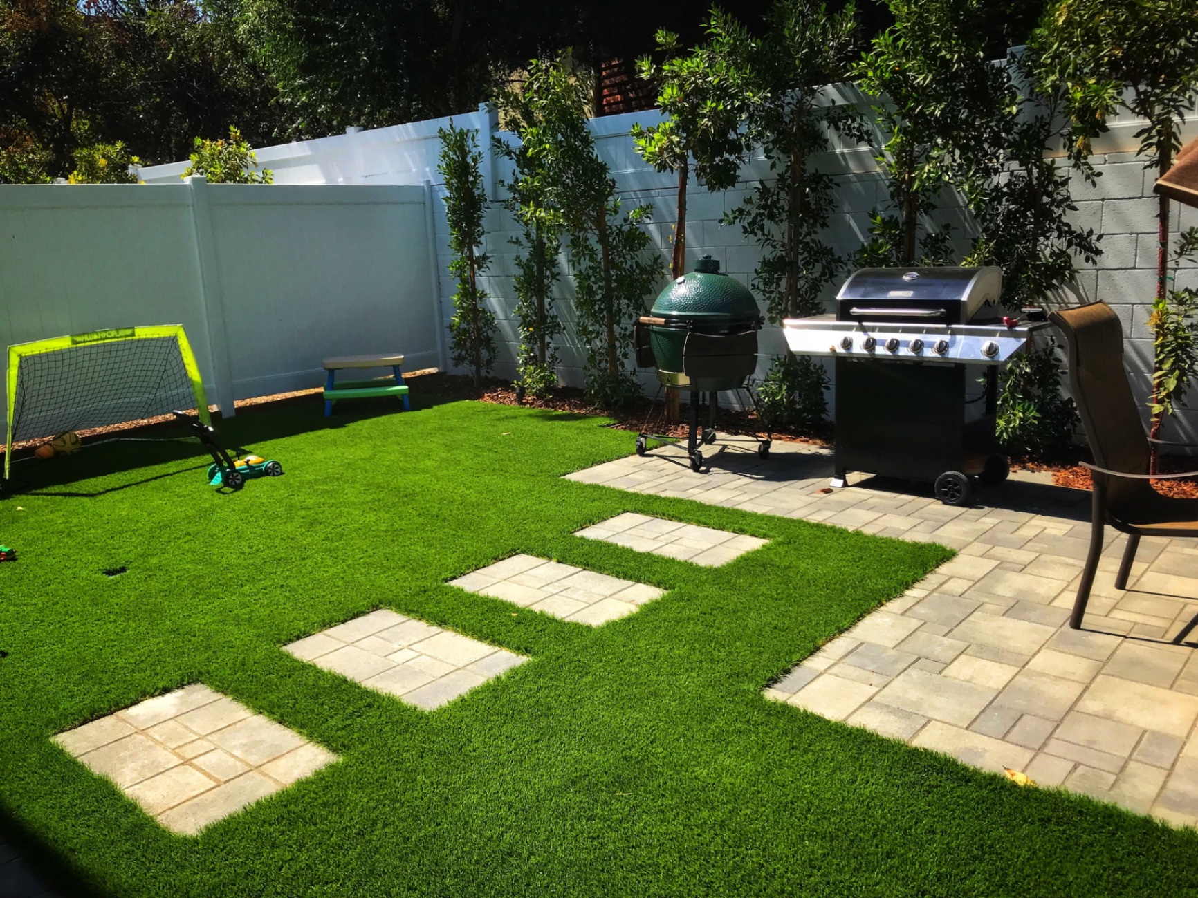 Backyard artificial turf with paver inlays, grill station and play area